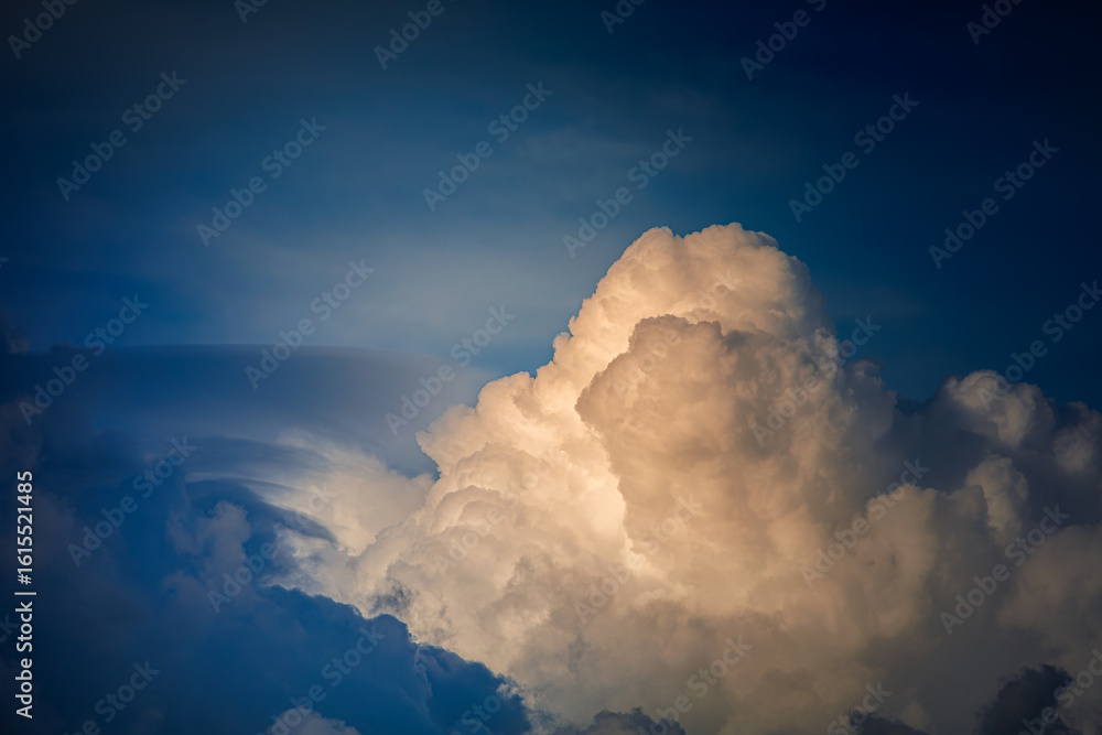 Naklejka premium White, fluffy clouds float across the blue sky. They resemble mountains. A close-up of the white cumulus clouds. Their texture is as soft as cotton. A summer sky.