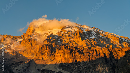 Foto Golden light kissing the snowy peak of mount kilimanjaro at sunset
