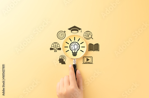 Innovative Learning and Knowledge Development Concept. Magnifying glass over glowing light bulb symbol with brain, representing education, global learning objectives, creativity, and e-learning. learn