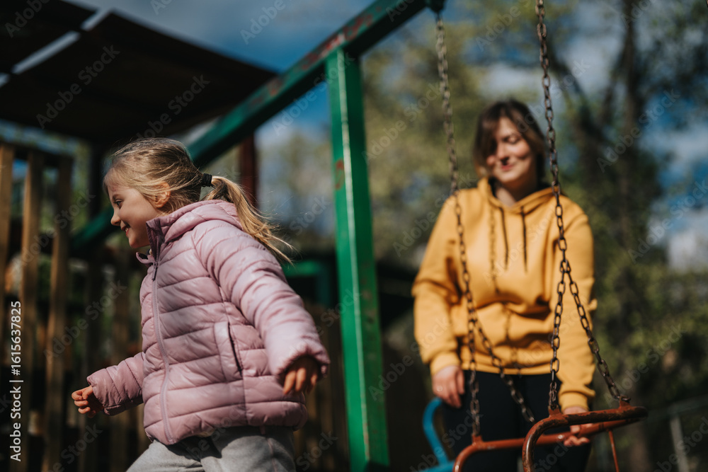 Obraz premium A joyful moment between a mother and her little daughter playing outdoors on a sunny day. The daughter is active, reflecting the happiness and bonding during their quality time in the park.