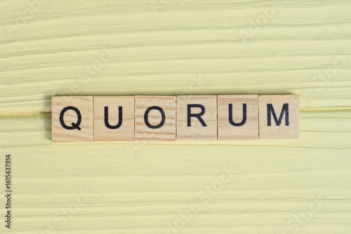 the gray word quorum of gray small wooden letters lie on a yellow table