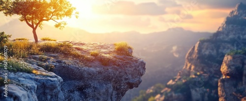 Resilient Tree on Cliff Edge Bathed in Golden Sunset Light Over Misty Mountains