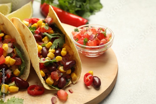 Tasty vegetarian tacos and ingredients on light grey table, closeup