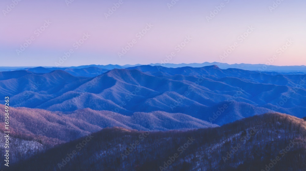 Fototapeta premium Panoramic view of a mountain range at twilight, smooth silhouetted forms with varying shades of blue,