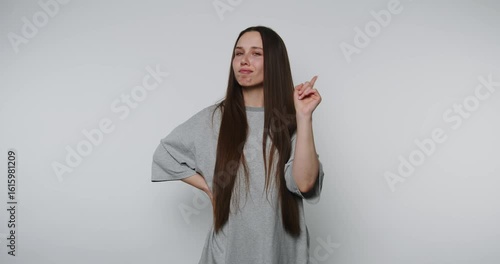 Young woman gestures playfully while looking thoughtful against a plain background she has an idea