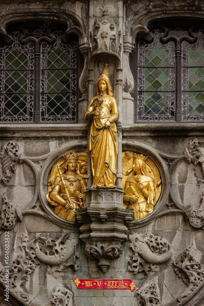 Obraz premium Golden religious sculpture on the facade of the Basilica of the Holy Blood in Bruges, Belgium. Intricate Gothic carvings and sacred figures representing medieval Christian art and devotion
