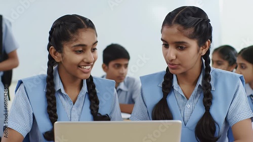 Two Indian School Girls in Blue Uniforms Using Laptop in Bright Classroom