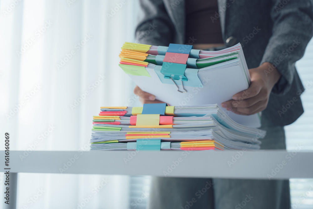 © Kritdanai - Organized Office Task: A person organizes a stack of paperwork, neatly arranged with colorful tabs and clips, against the backdrop of a bright, minimalist office setting. © Kritdanai - Organized Office Task: A person organizes a stack of paperwork, neatly arranged with colorful tabs and clips, against the backdrop of a bright, minimalist office setting.