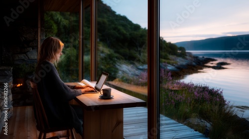 Cozy evening by the lake with a woman working on a laptop and enjoying a cup of coffee