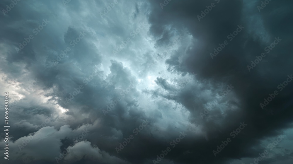 Obraz premium Rolling storm clouds fill the sky with varying shades of gray, indicating an approaching storm during late afternoon. The dark formations create an eerie ambiance.