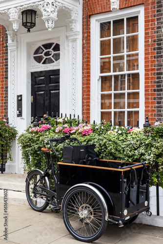 Fotografie A vintage black cargo tricycle parked in front of a posh Victorian house in St James's district, central London