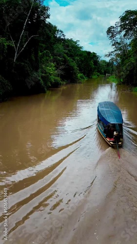 Vertical view of a traditional riverboat moving upstream through the muddy waters of the Amazon