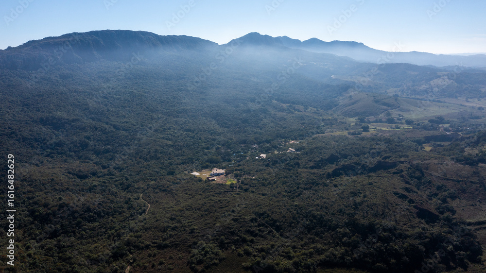 Fototapeta premium Aerial view of the São José mountain range, which borders the city of Tiradentes, in Minas Gerais, Brazil, on a beautiful dawn with clouds and blue sky.