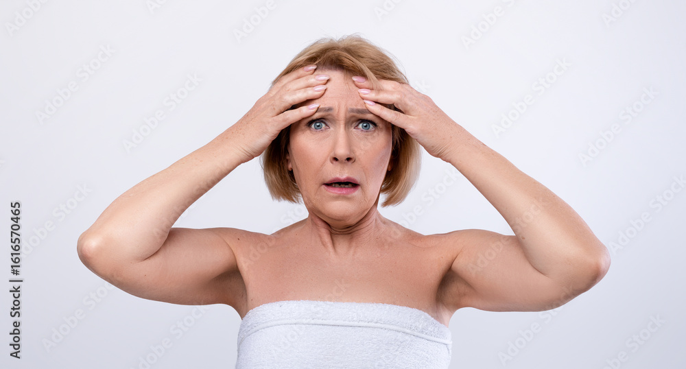Portrait of terrified senior lady touching her forehead, scared to see new wrinkles on light studio background. Shocked mature woman disliking her appearance, cannot embrace her aging Portrait of terrified senior lady touching her forehead, scared to see new wrinkles on light studio background. Shocked mature woman disliking her appearance, cannot embrace her aging