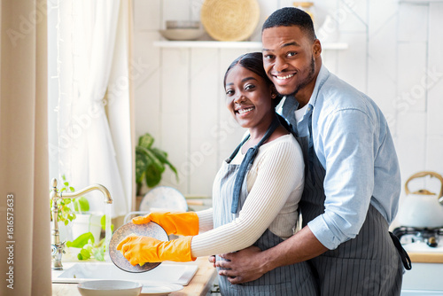 Fotografie Happy young black couple washing dishes together at home, copy space