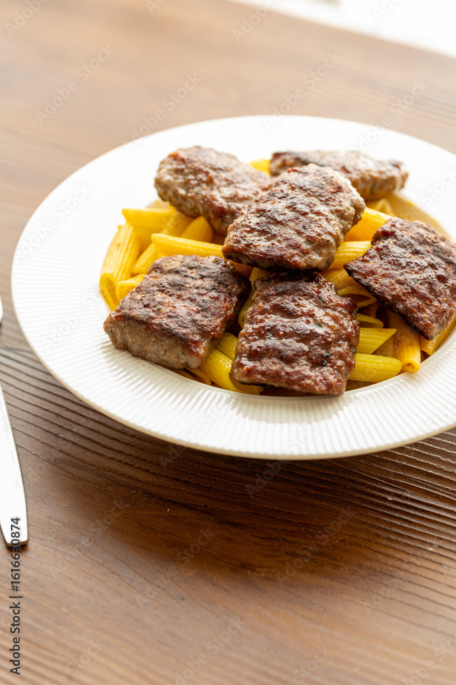 grilled meatballs with penne pasta on a white plate close-up grilled meatballs with penne pasta on a white plate close-up