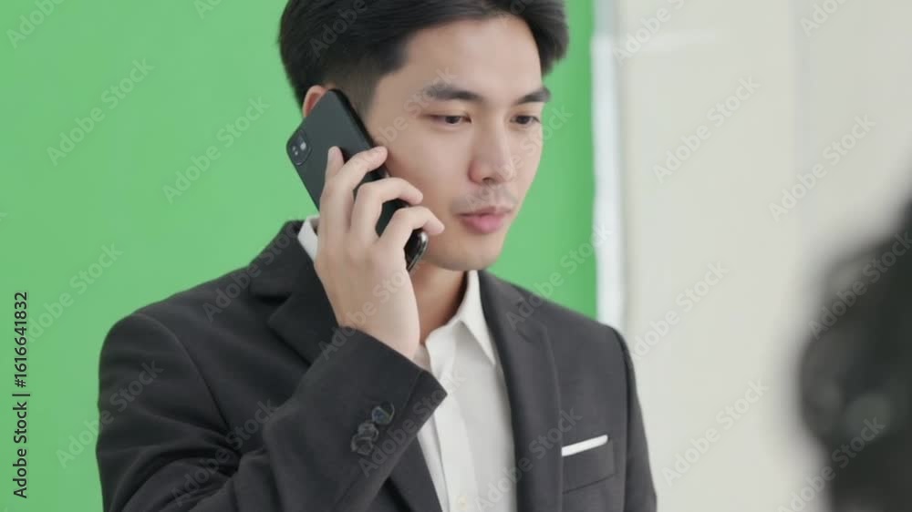 Businessman engaged in a phone conversation in a studio with a green screen backdrop Businessman engaged in a phone conversation in a studio with a green screen backdrop