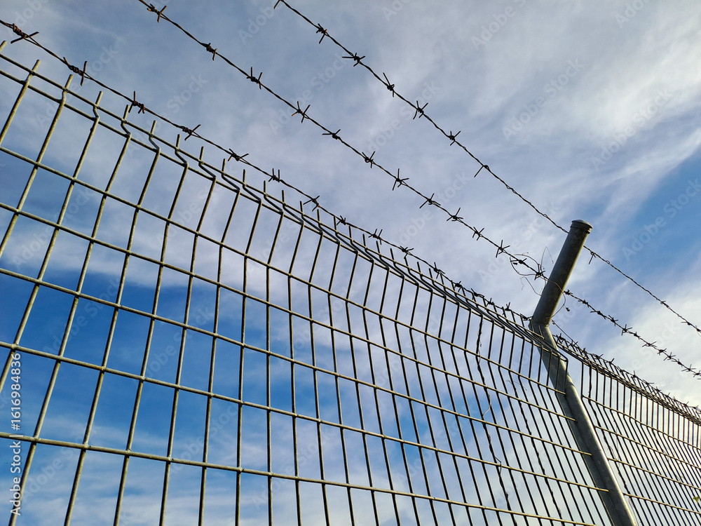 Obraz premium Closeup of a metal chain link fence with a clear blue sky background.