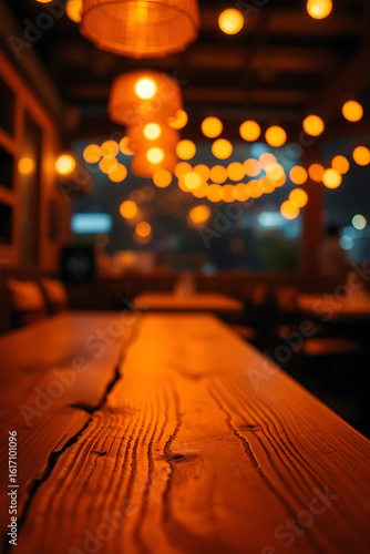 A close-up  low-angle shot of a rustic wooden bar counter  showing prominent cracks and grain. Overhead  several warm-toned Edison-style pendant lights illuminate the scene  casting a golden glow on t