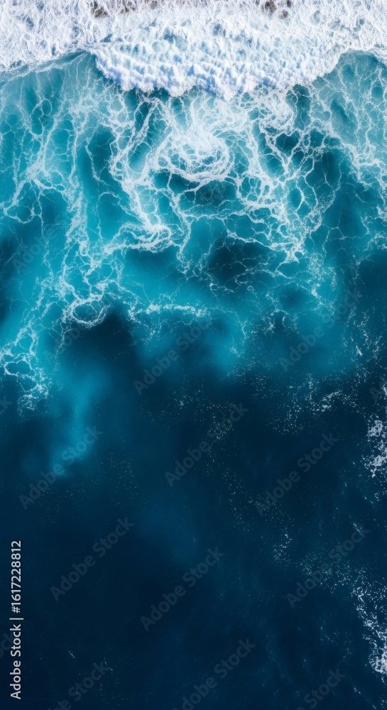 Naklejka premium A mesmerizing aerial view captures the dynamic contrast between foamy white ocean waves and the deep, tranquil blue water below.