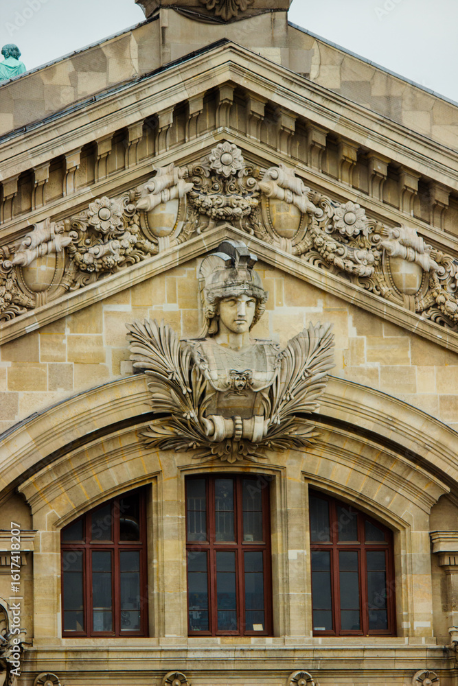 Obraz premium Richly ornate architectural facade of the Opéra Garnier (Palais Garnier) in Paris. The image highlights a beautifully sculpted bust of a classical figure adorned with laurel branches