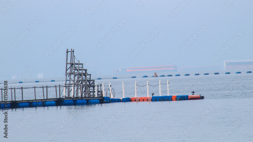 Fototapeta premium a float or pontoon, made from a used barrel or drum, used to float a net or structure in water, such as in fish farming in floating cages.