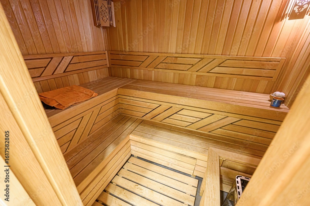 cozy sauna interior with wooden benches, walls, and floor. Towel, bucket, and heater are visible. The room is well-lit, creating a warm atmosphere cozy sauna interior with wooden benches, walls, and floor. Towel, bucket, and heater are visible. The room is well-lit, creating a warm atmosphere