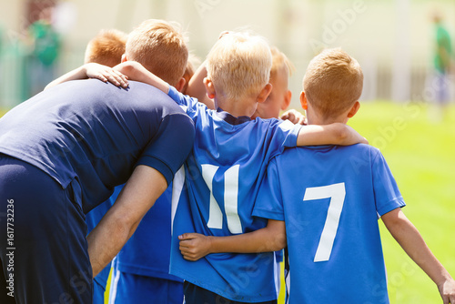 Happy Children United With a Coach in a Sports Team. Kids Building Team Spirit Altogether With a Trainer. Boys in Blue Uniforms Play Sports Game Outdoor