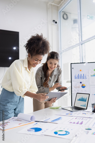 Two business woman working together for analysis data plan business strategies at desk in office, Business discussing and startup concept.