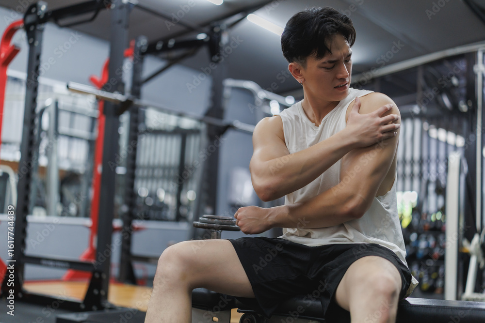Fototapeta premium Young athlete experiencing shoulder pain after workout in gym