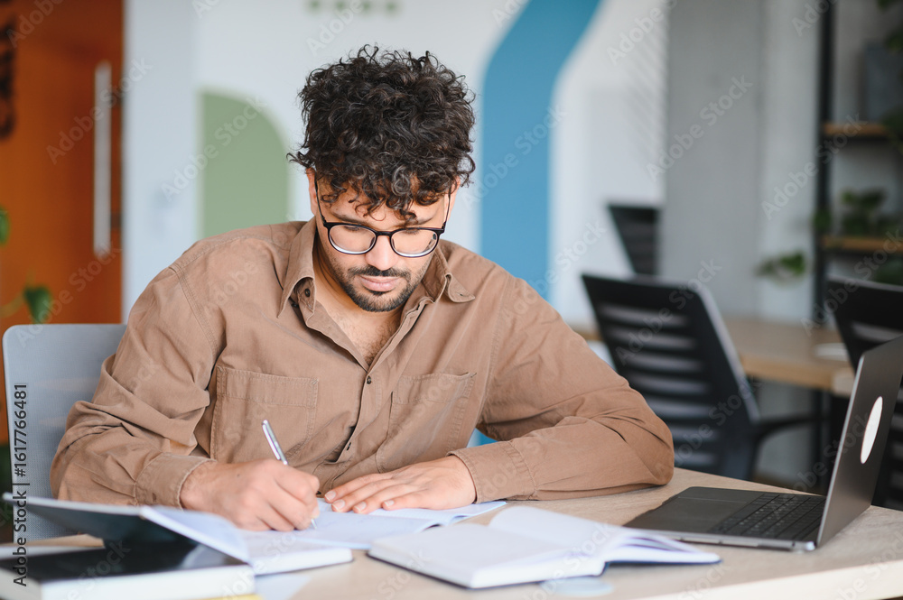 Obraz premium Focused arab student studying and taking notes in university library