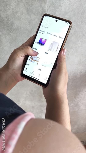 Rear view of a young girl choosing goods, gadgets, clothes in an online store on her phone. Online purchases.