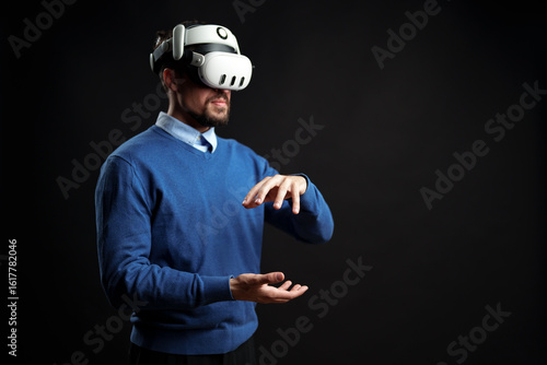 фотографія Man experiences virtual reality in a black room while wearing a VR headset and i