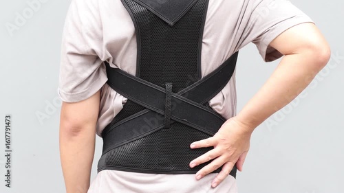 Young asian man wearing a back support belt, Lumbar brace for back trauma or Herniated Disc To relieve back pain. background