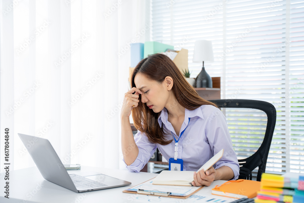 © Kritdanai - Business Frustration: A woman, visibly stressed and overwhelmed, sits at her desk, hand on her forehead, a laptop and documents surrounding her. © Kritdanai - Business Frustration: A woman, visibly stressed and overwhelmed, sits at her desk, hand on her forehead, a laptop and documents surrounding her.