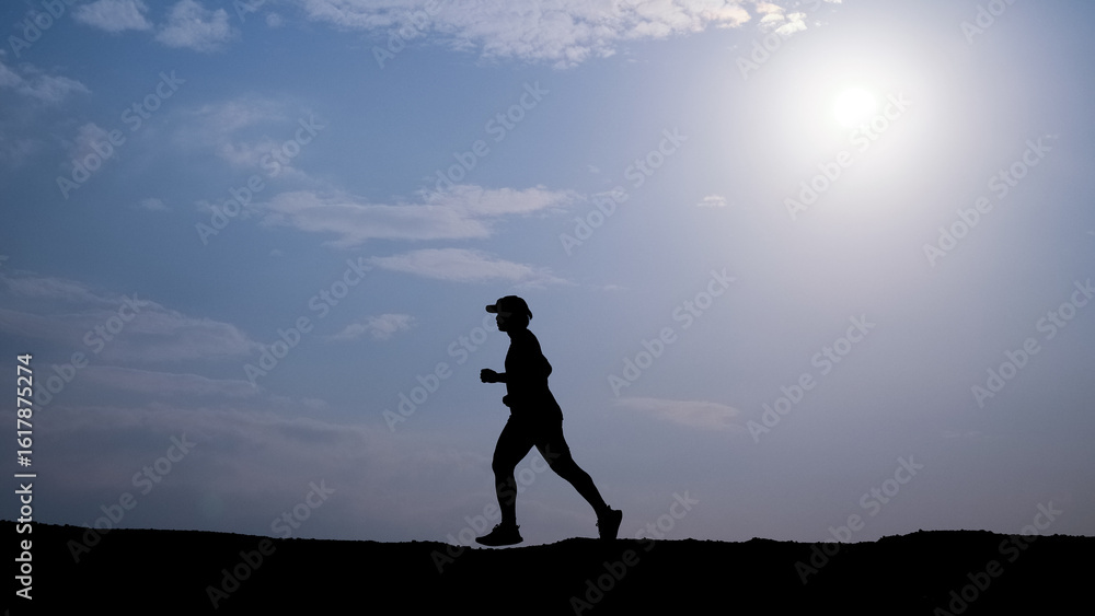 Running Silhouette Under Sunlight: A lone figure sprints with determination, their silhouette against the bright sky. It captures the energy and solitude of outdoor exercise. Running Silhouette Under Sunlight: A lone figure sprints with determination, their silhouette against the bright sky. It captures the energy and solitude of outdoor exercise.