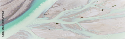 Iconic Italian river Tagliamento, Friuli, Carnia, Italy. Aerial view of the braided riverbed with turquoise water flowing through gravel banks and sparse vegetation.
