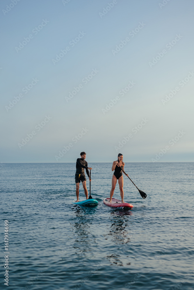 Naklejka premium Two tourists paddleboarding on a vacation