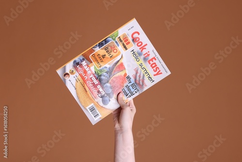 Woman with lifestyle magazine on brown background, closeup