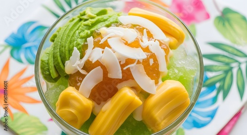 Exotic Asian shaved ice dessert with fresh avocado, sweet jackfruit, and coconut flakes on a tropical leaf background.