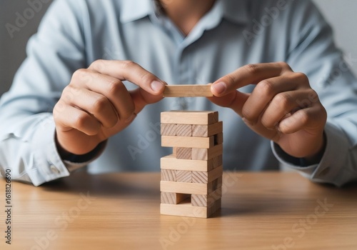 Hands carefully placing wooden block on unstable tower