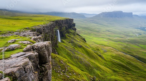 Fototapeta Naklejka Na Ścianę i Meble -  Dramatic Waterfall cascading down a majestic cliff face overlooking lush green valley and distant