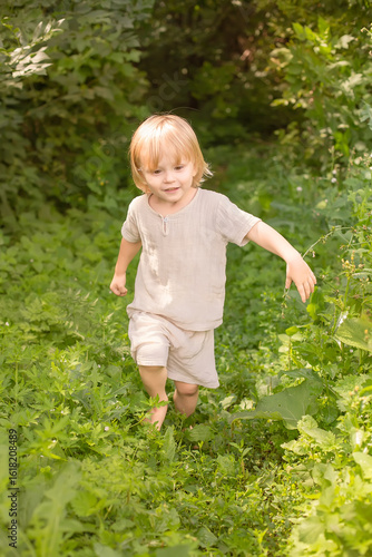 Little boy running barefoot through the green grass