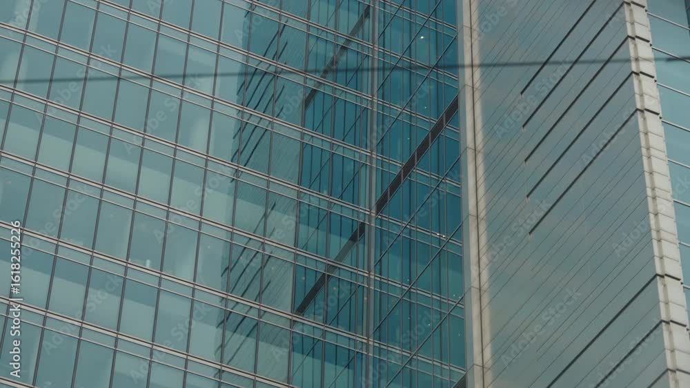 POV close-up shot from inside car driving through streets of modern city. Windshield view urban landscape, skyscrapers windows glass, lighting poles and communications in slow motion, cloudy day