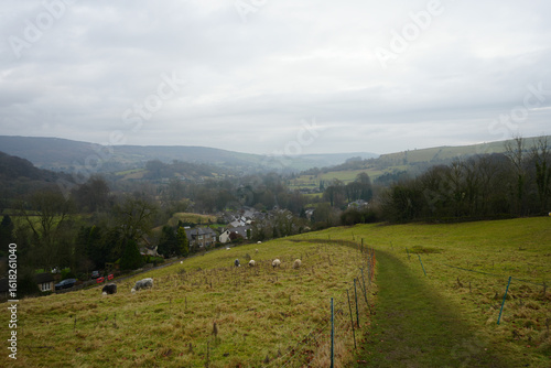 Bucolic scene of rolling hills, grazing sheep, and historic village overlooking Stoney Middleton in The Peak District, England