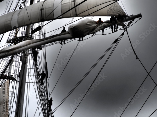 dramatic black and white of sailors furling a sail