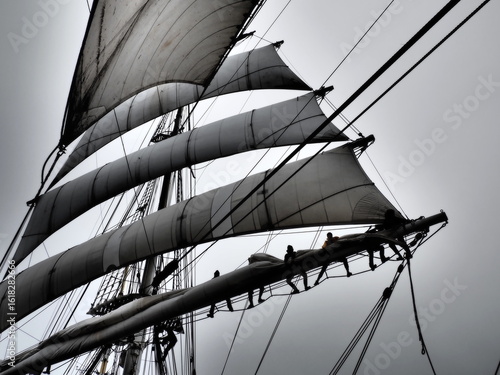 dramatic black and white of sailors furling a sail
