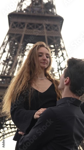 Happy romantic couple smiling and embracing under the Eiffel Tower in Paris on a sunny day