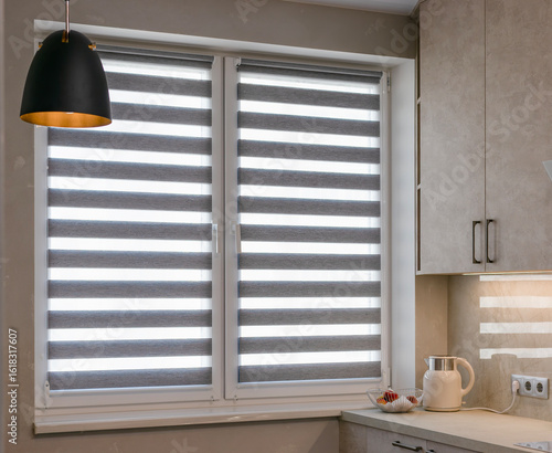 Zebra blinds installed on kitchen windows, featuring alternating sheer and opaque fabric stripes. Double roller shades provide adjustable light control while adding a modern touch to interior space.