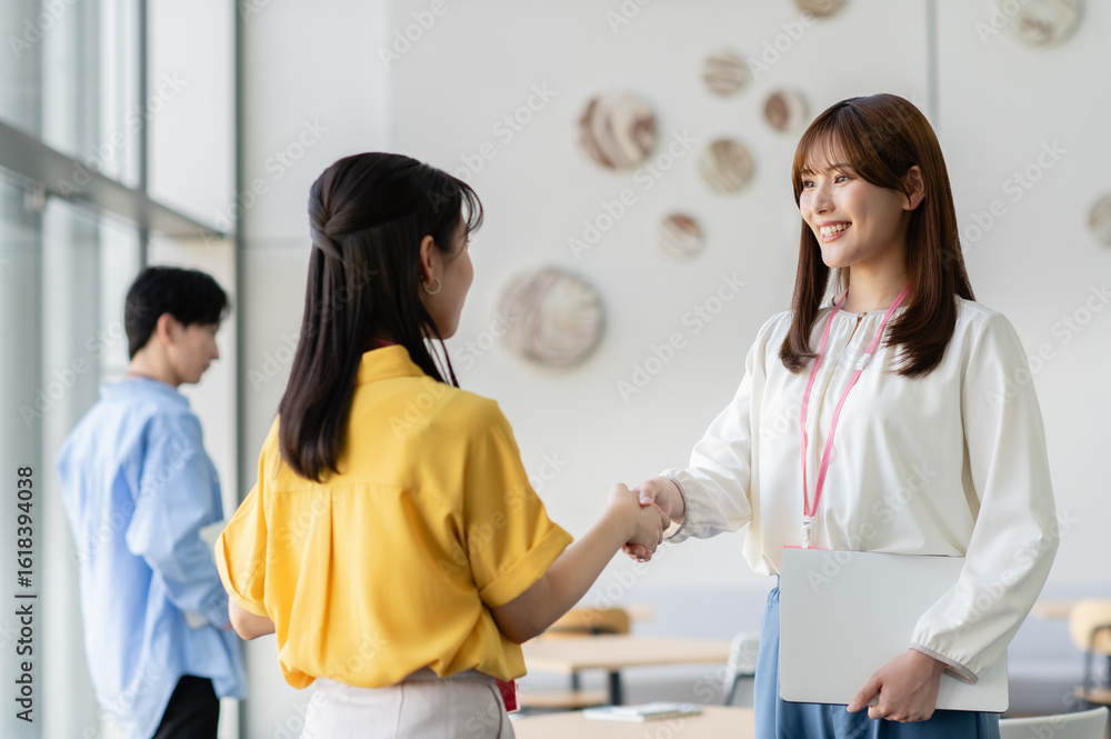 Fototapeta premium オフィスで握手する若いビジネスウーマン【撮影協力：スカパー東京メディアセンター】